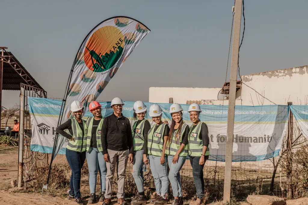 The GT Chaane team in hard hats and reflective vests in front of a banner on Mandela Day 2022