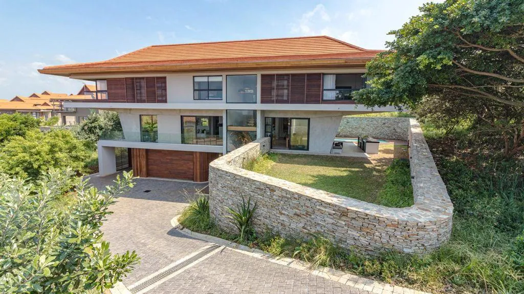 A private house with a wide tiled roof behind a curved stone wall